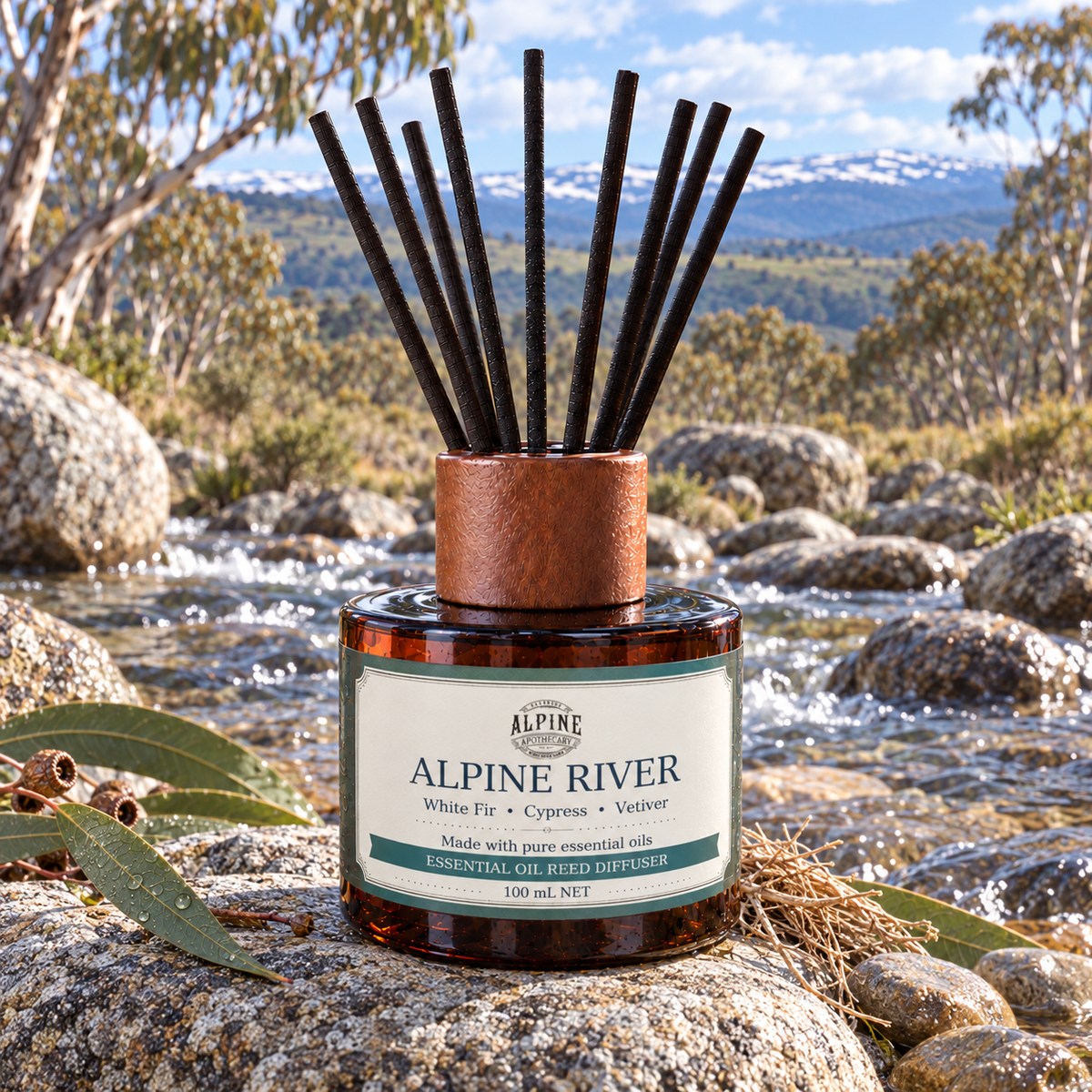 Alpine River essential oil reed diffuser with timber top and black reeds beside a rocky Snowy Mountains stream